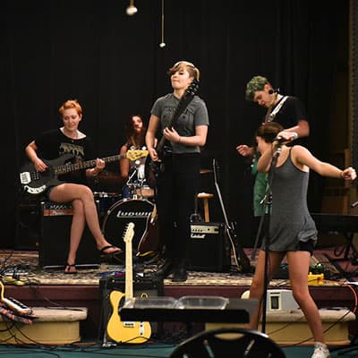 A teenage rock band practices in an empty theater.