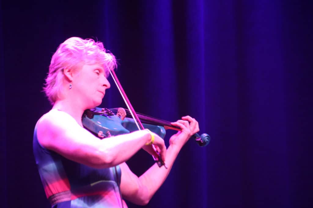 Josie Quick plays her violin onstage during a concert. 