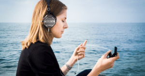 A woman listening to music through headphones by water