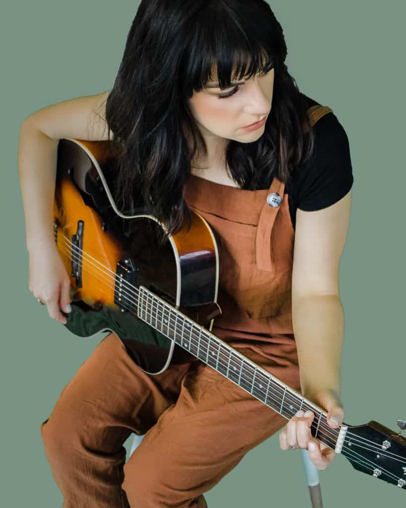Rachel Baiman plays an acoustic guitar. 