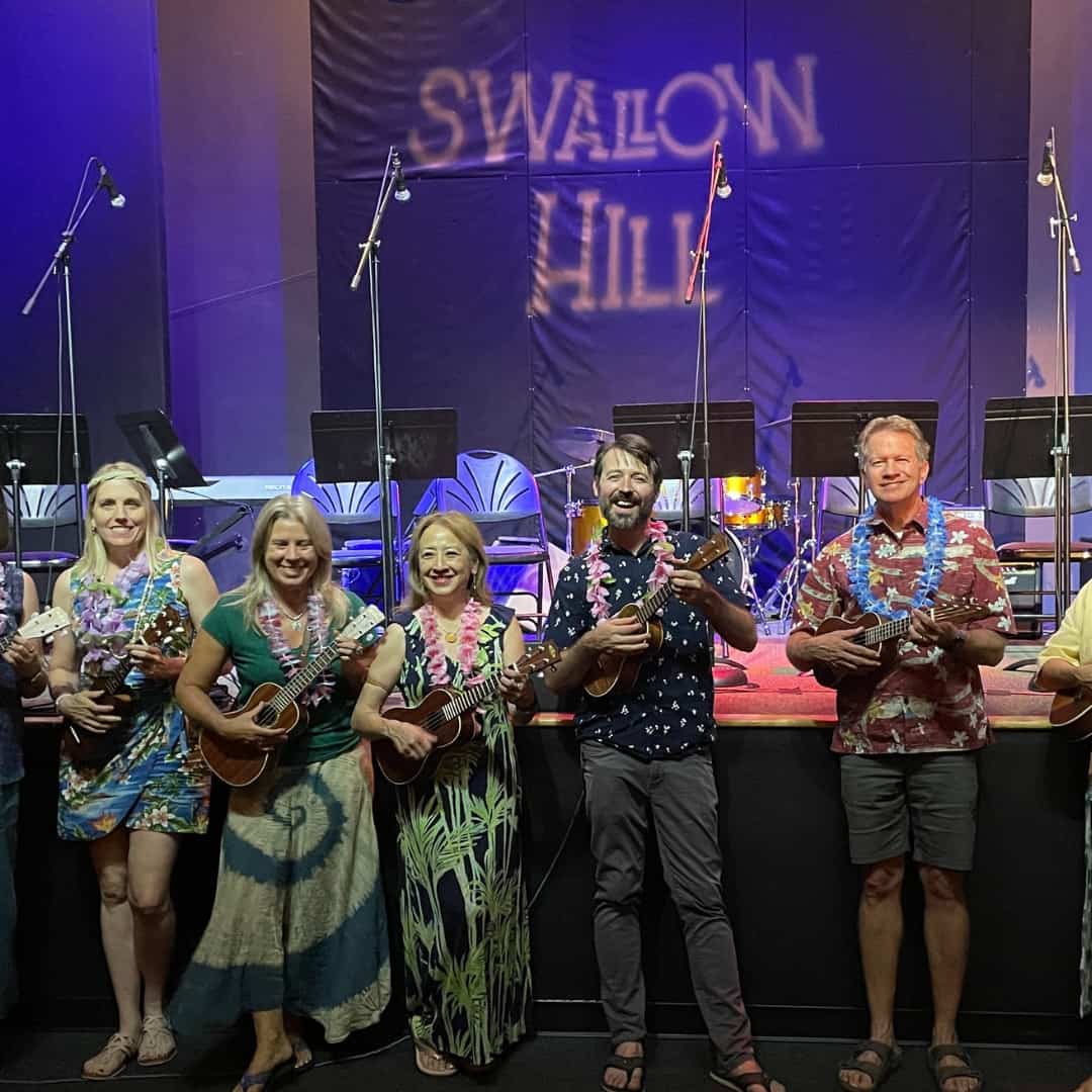 A group of adults music students and their teacher smiling and holding their ukuleles after a class at Swallow Hill Music.