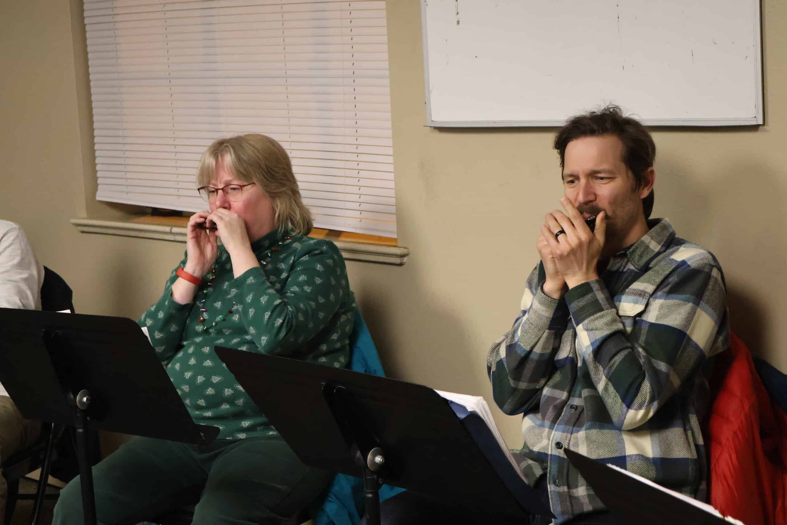 Two students, one male and one female, play harmonicas during a group class at Swallow Hill Music.