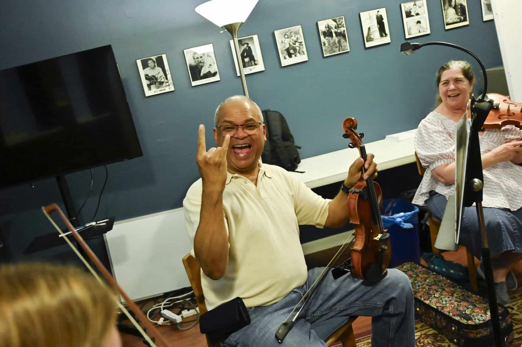 A male violin student smiles at the camera while 