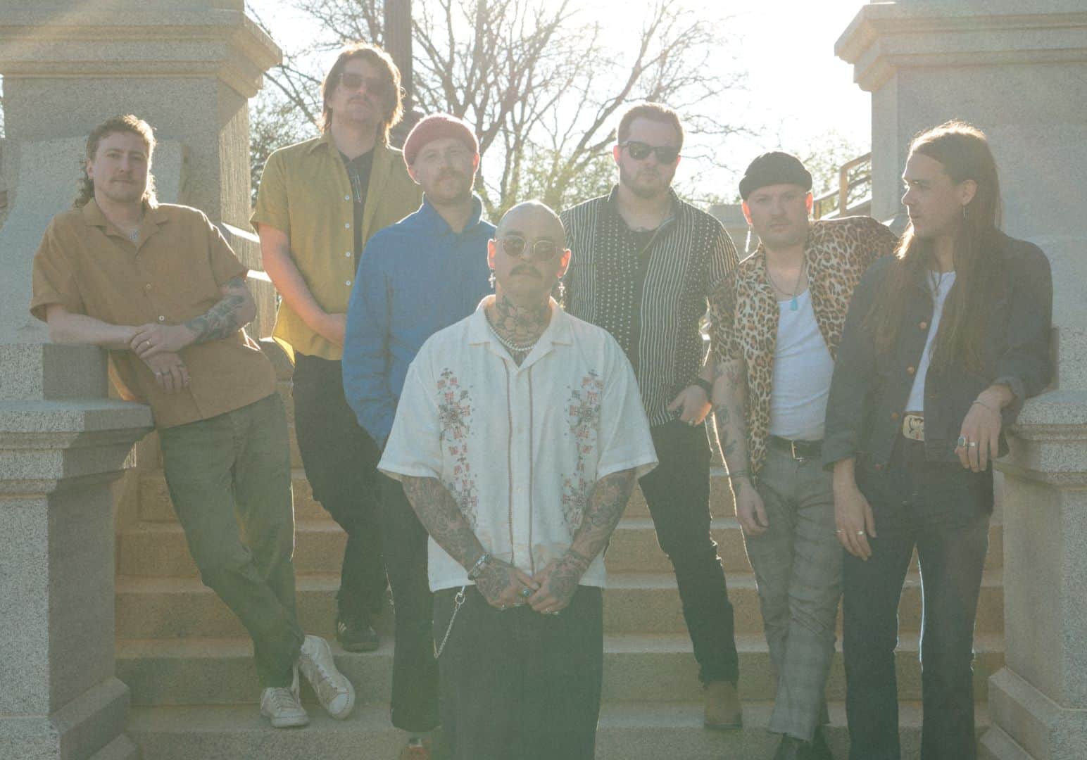 The 7 members of Rootbeer Richie and the Reveille, one of the bands performing at Indiewood, standing on a staircase outdoors with the sun shining on them