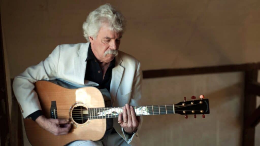 Tom Rush playing an acoustic guitar.