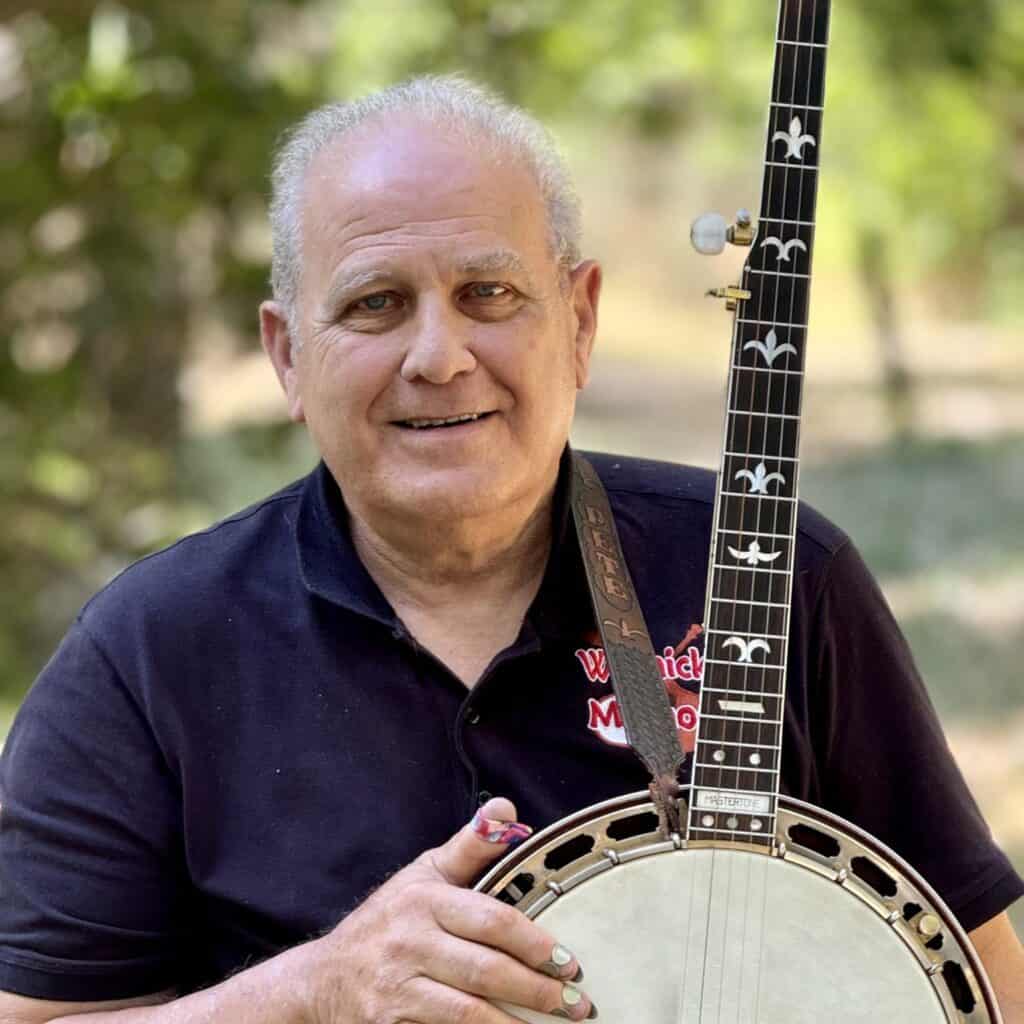 Pete Wernick Headshot with Banjo A photo of Pete Wernick holding his banjo and smiling at the camera